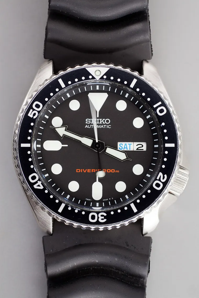 Orologio subacqueo in acciaio con cinturino, fotografato su fondo neutro