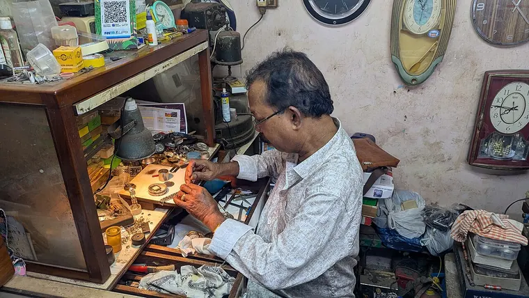 Un orologiaio al lavoro su un orologio, con lente e attrezzi